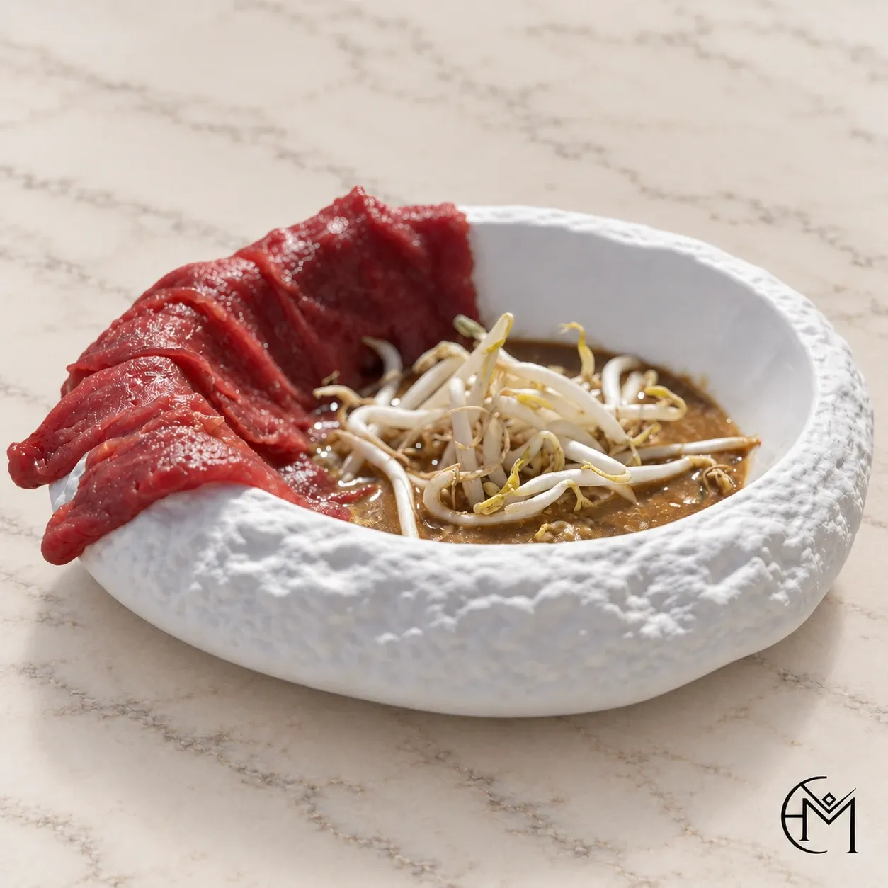 Thinly sliced red meat fanned against a dark broth topped with bean sprouts, in a textured white bowl.